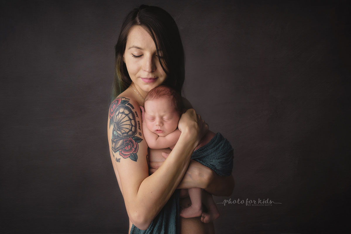 mother with tatoo hold her new born baby and poses during a workshop by Nicoleta Raftu