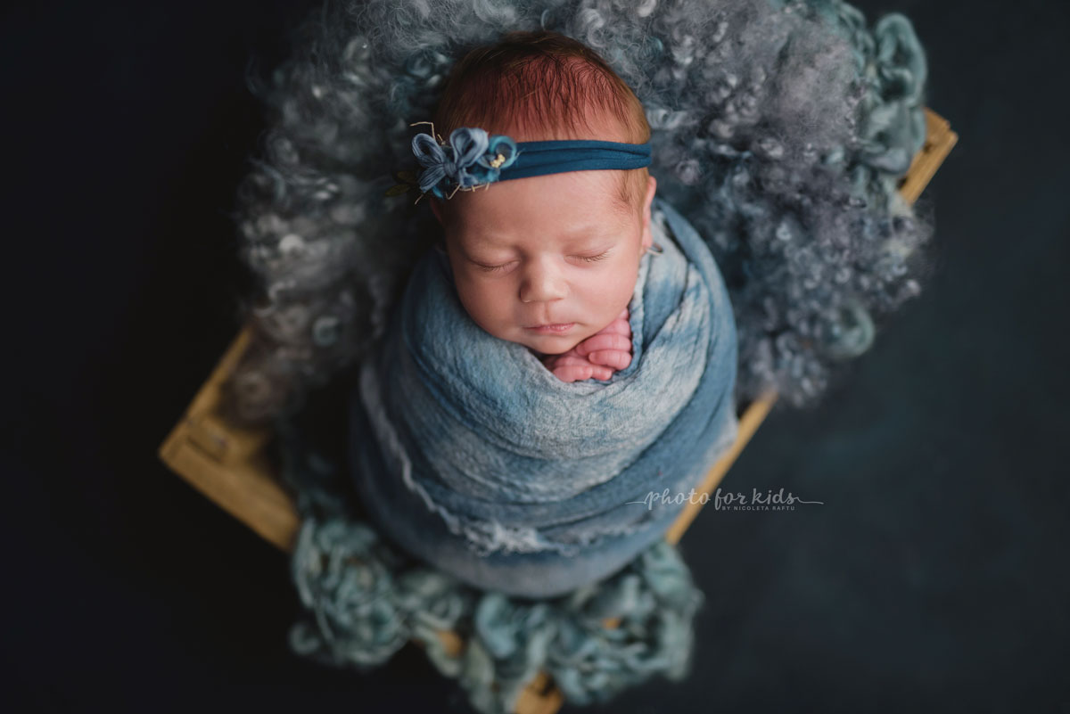 new born little girl in blue outfits sleeps on her back during a photography workshop by Nicoleta Raftu