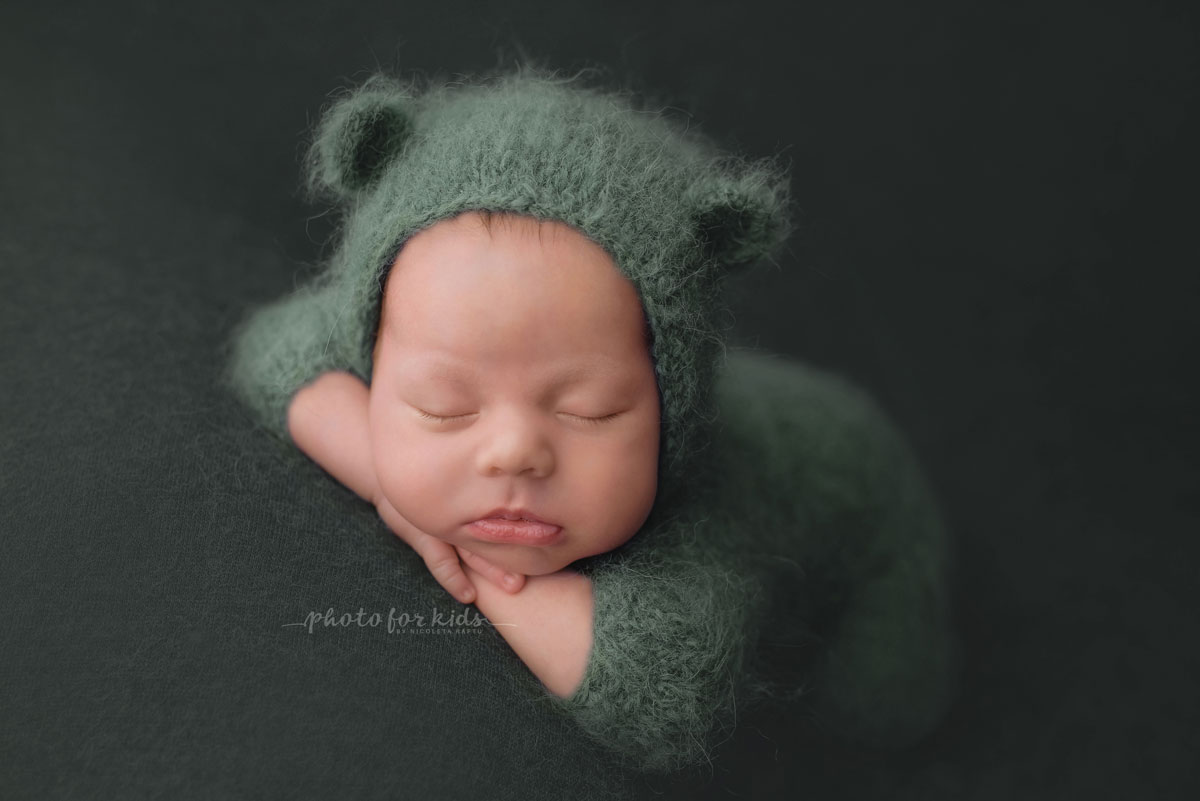 newborn in green outfits sleeps during a photo shooting in a workshop by Nicoleta Raftu