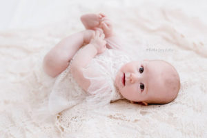 Nicoleta Raftu maternity and new born photographer for workshops by Carmen Bergmann Studio newborn lies on her back and wathces at the camera